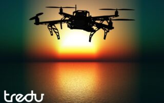 Drone lentää veden yllä auringonlaskussa, Tredu-logo alakulmassa.